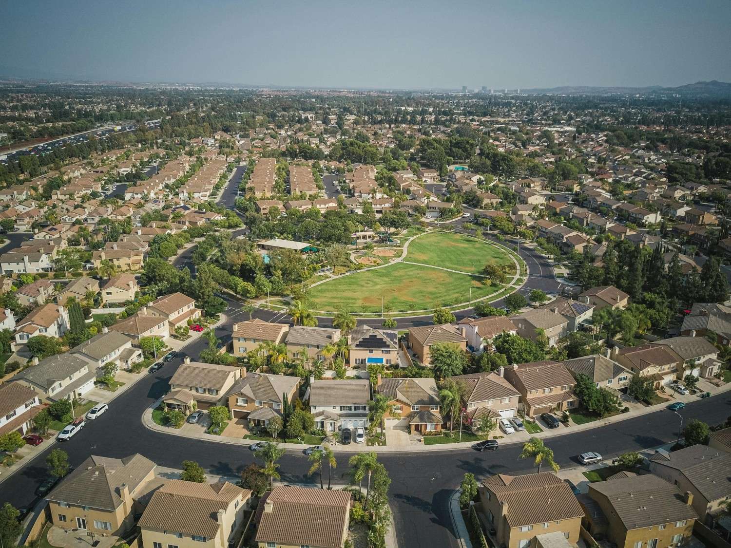 Aerial view of a residential neighborhood centered around a large shared park, illustrating HOA-managed open space in a townhome community.