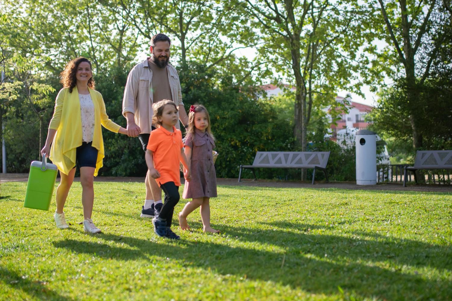 Family walking through a grassy community park, highlighting shared green space and everyday livability in a townhome HOA community.