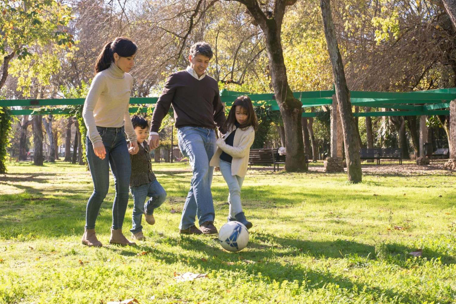 Family playing soccer in a shared park, highlighting recreational green space maintained through townhome HOA management.