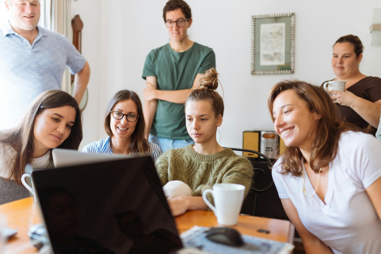 Group of residents gathered around a laptop during a planning meeting, representing leadership, collaboration, and community oversight in a master-planned neighborhood.