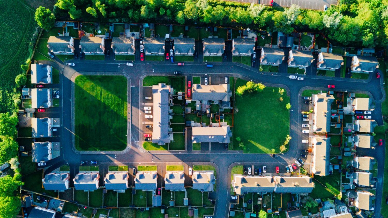 Aerial view of a townhome community with internal roads, parking areas, and shared green space, illustrating organized HOA-managed neighborhood planning.