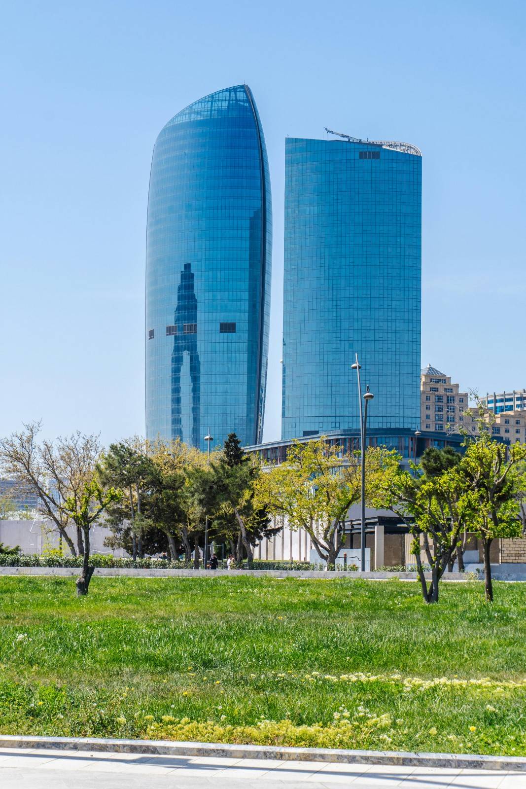 Modern glass towers rising behind a landscaped green space, illustrating integrated urban design in a master-planned community.