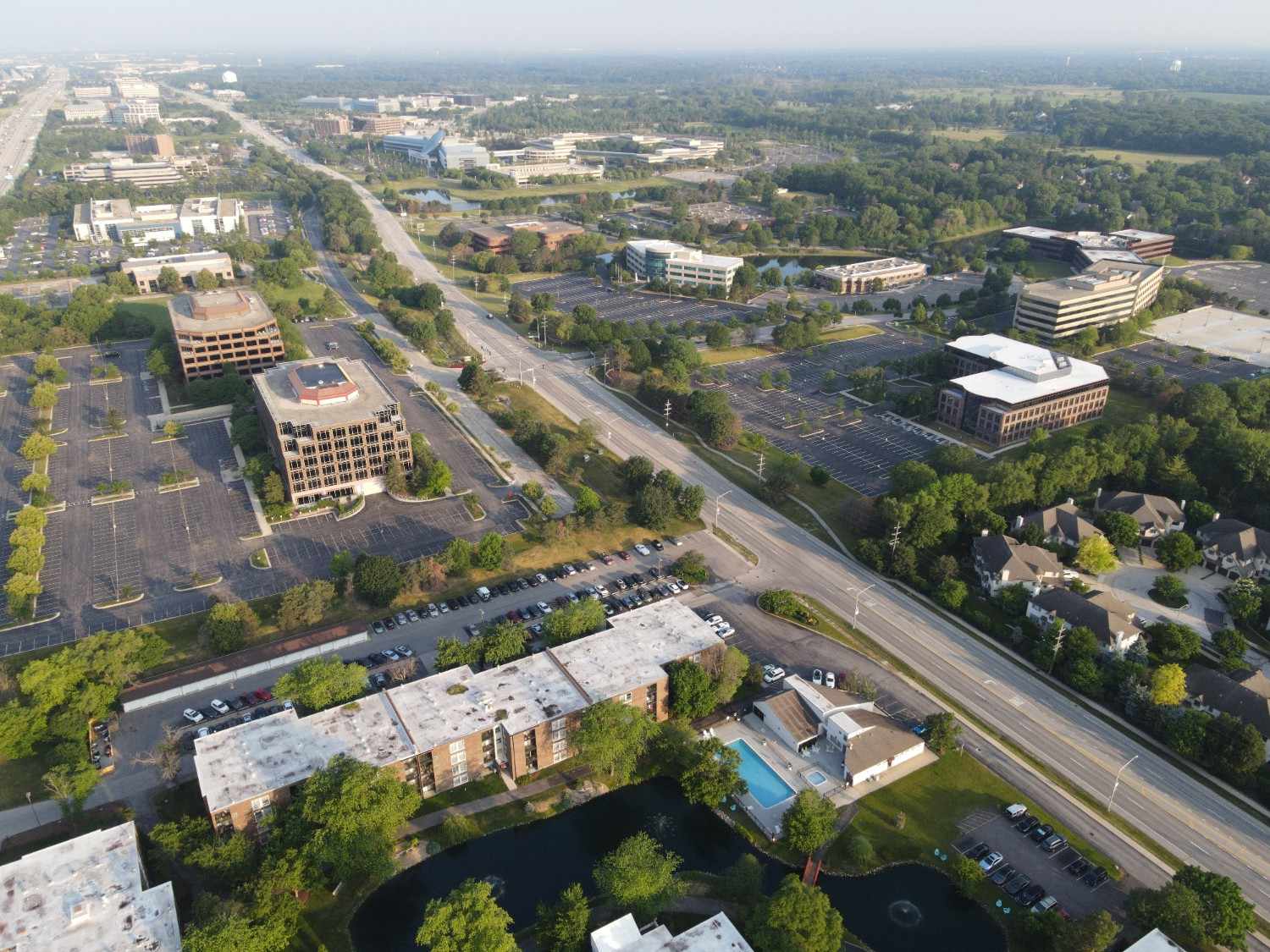 Aerial view of a residential condominium neighborhood with multi-story buildings, tree-lined streets, and surrounding urban infrastructure.