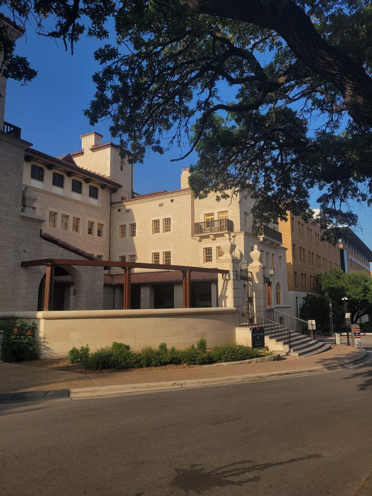 Multi-story stone building with landscaped entrance and mature trees.