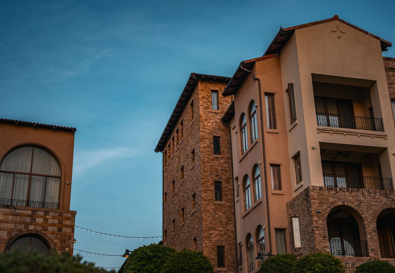 Upscale brick mid-rise condominium residences with balconies, arched architectural details, and a multi-story exterior.